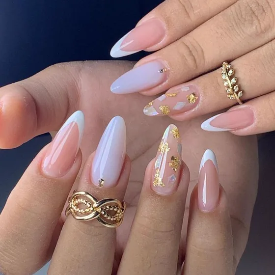 Conjunto de unhas em soft gel em tons nude e branco leitoso, com detalhes em folha dourada.